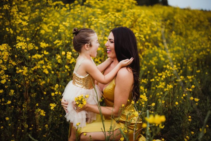 A mother and her daughter in a field of yellow flowers
