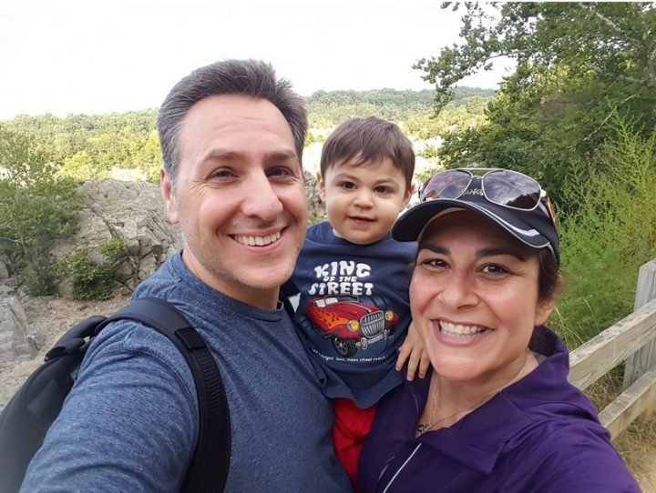 Wife and husband posing with their baby during a hike